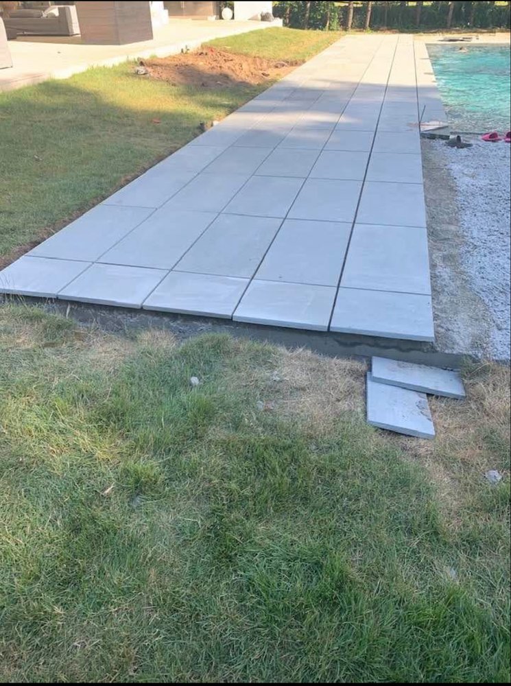 Large-format bluestone pool deck being set plank by plank