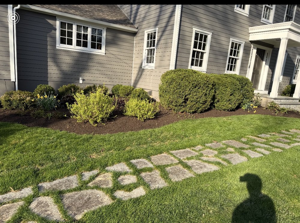 Granite stepping stone path beside a freshly mulched foundation bed