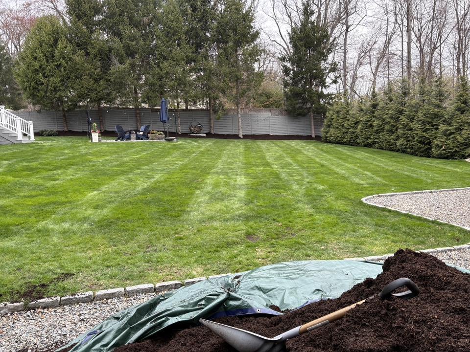 Mulch delivery and spring cleanup on a striped backyard lawn