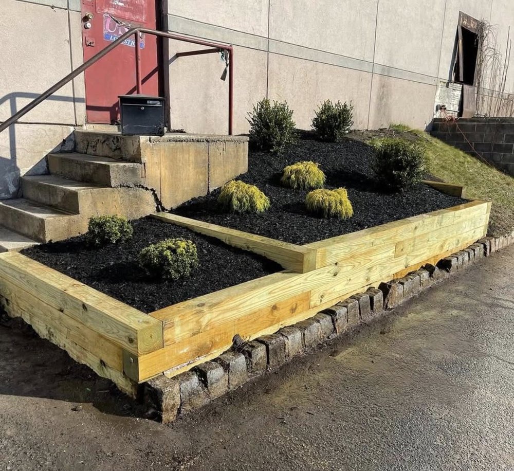 Timber retaining beds with layered shrubs at a commercial entry